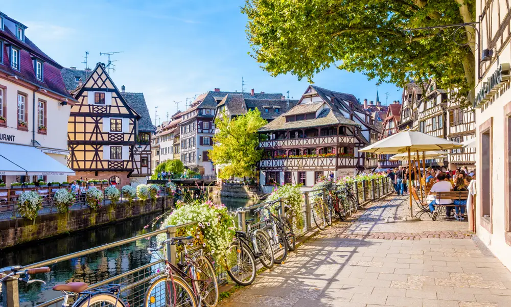 Place Benjamin Zix, dans le quartier de la Petite France à Strasbourg. Vélos accrochés à la rembarde et terrasse de café.