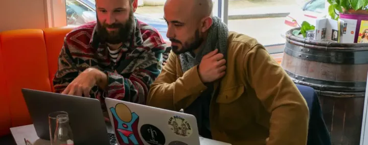 deux hommes en train de travailler avec leurs ordinateurs portables.
