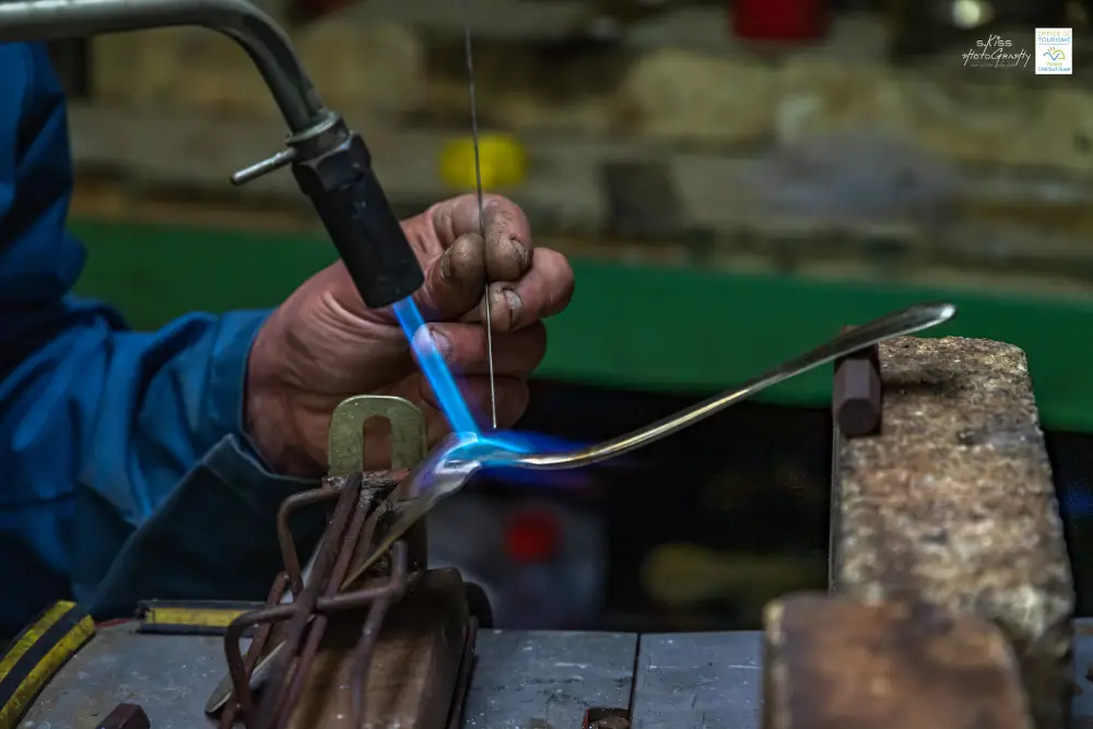 gros plan sur les mains d'un ouvrier en train de fabriquer un couvert, à Darney dans les Vosges