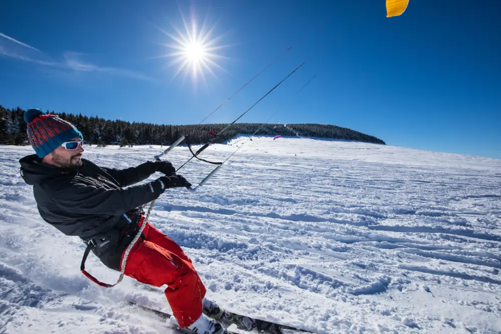 homme en train de faire du snow kite au Mezenc en Haute-Loire, au soleil.