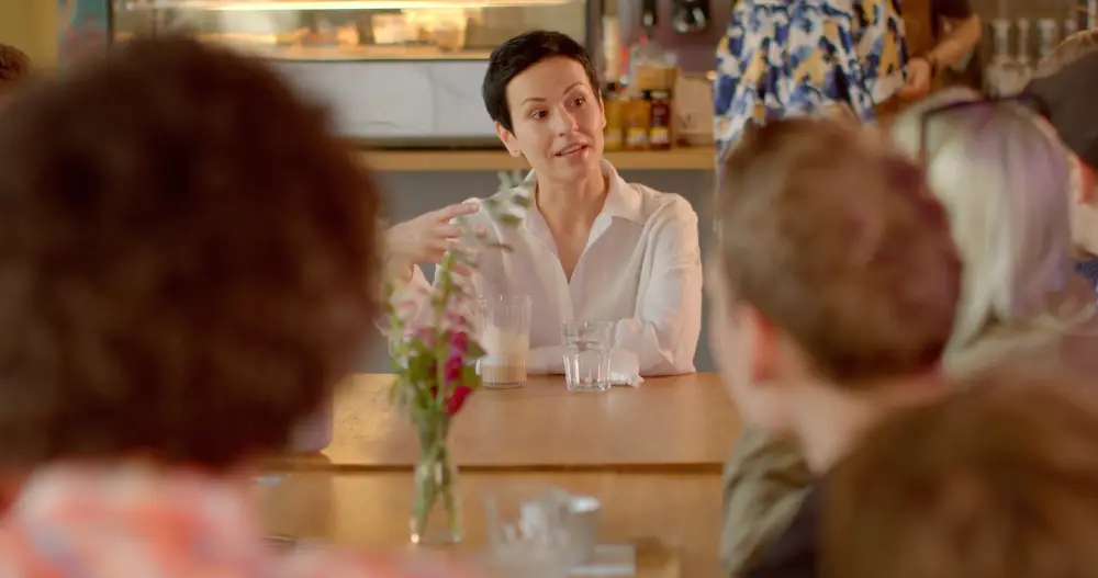 femme de face dans une réunion avec d'autres personnes de dos