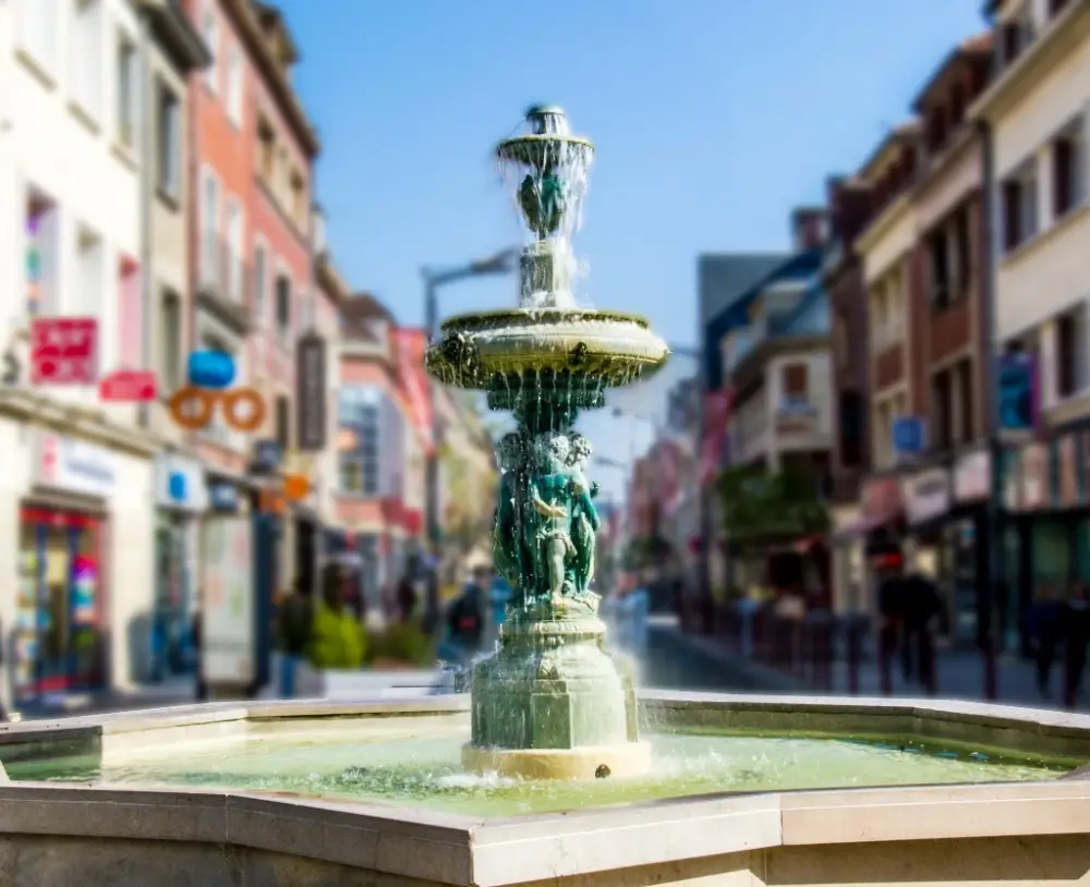 Les rues du centre-ville de Beauvais avec une fontaine en premier plan.