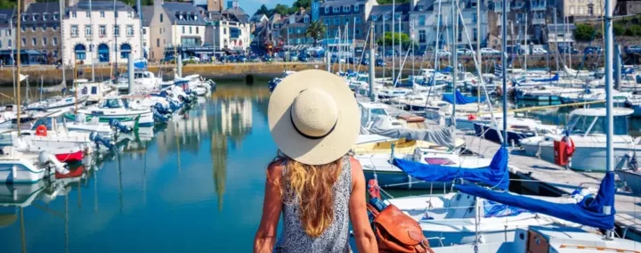 Femme de dos avec un chapeau de soleil assise face au port de Saint-Brieuc, dans les Côtes-d'Armor.