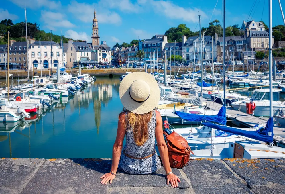 Femme de dos avec un chapeau de soleil assise face au port de Saint-Brieuc, dans les Côtes-d'Armor.